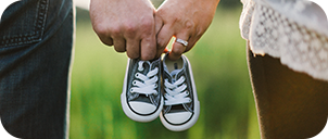 close up of a couple's hands holding baby shoes