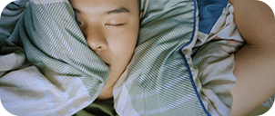 person sleeping surrounded by pillows and blankets